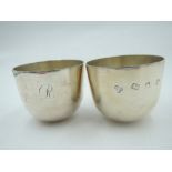 A pair of silver tumbler cups of plain form having curved weighted bases, initial J/R to side and