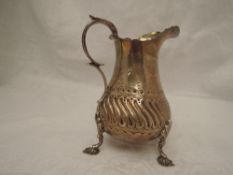 A Victorian silver cream jug of baluster form having moulded decoration, plain cartouche, loop