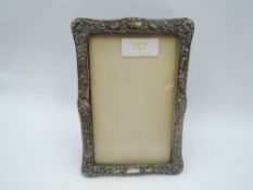 A silver photograph frame having bird and scroll decoration and black velvet easel back,