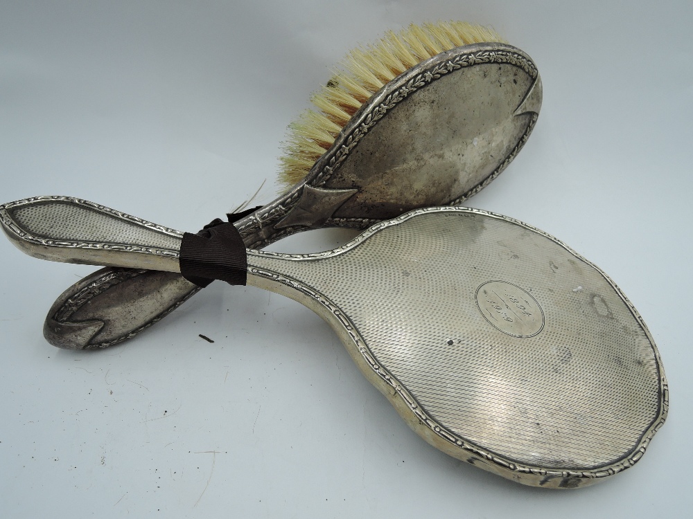 An HM silver hand mirror having engine turned stripe decoration and dated cartouche and an HM silver