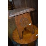 An Arts and Crafts stool, having carved detail and tooled leather top, probably Liberty's