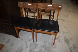 A pair of vintage kitchen dining chairs having vinyl seats