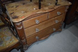 A stripped pine chest of two over two drawers having shaped top and glass handles