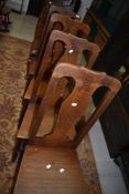 A set of four period style oak dining chairs having solid seats and vase backs