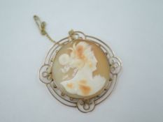 A conch shell cameo brooch depicting a Grecian maiden within an open rose gold decorative collared