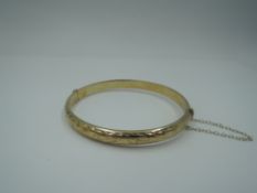 A 9ct gold hinged bangle having engraved decoration, approx 8.3g