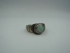 A white metal band ring having a matt white opal in a collared mount with moulded shoulders, no