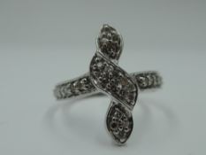 A diamond chip set vertical twist dress ring on a white metal loop stamped 18K, size L & approx 3.