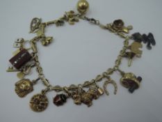 A yellow metal fancy link charm bracelet having 20 small charms including dog, elephant, funnel etc,