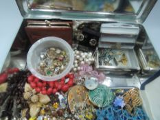 A vintage tin containing a selection of costume jewellery including earrings, brooches, pendants