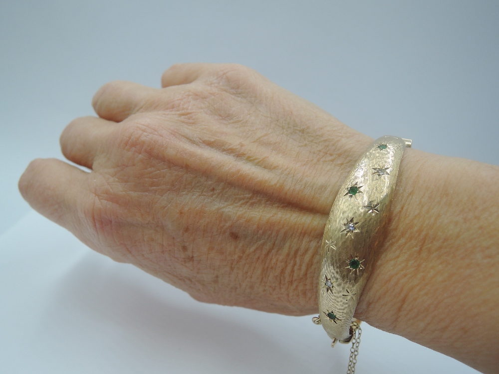 A 9ct gold hinged bangle having diamond and emerald chip decoration in star burst settings on - Image 3 of 3