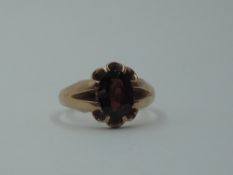 A rose metal signet ring stamped 9ct having an inset oval garnet in open mount, size P & approx 4.