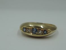 An 18ct gold dress ring having three powder blue sapphires interspersed by two diamond chips in a