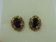 A pair of 9ct gold garnet stud earrings in decorative mounts, approx 1.6g
