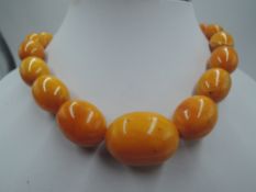 A long string of butterscotch amber beads of oval form with concealed barrel clasp, approx 32' &