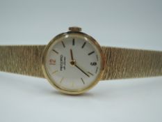 A lady's 9ct gold wrist watch by Record having baton numeral dial to small circular face in gold