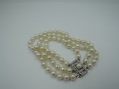 A cultured pearl triple strand bracelet of small size having white metal box clasp stamped 835