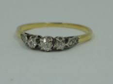 A diamond trilogy ring, total approx 0.250ct in claw set raised mount to moulded shoulders on a