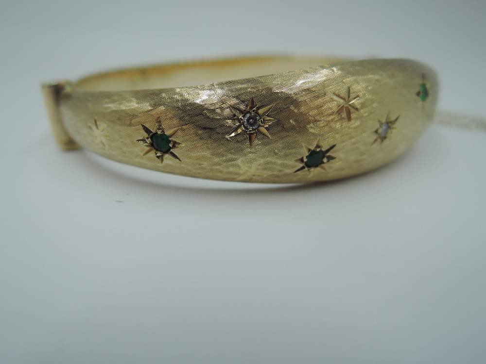 A 9ct gold hinged bangle having diamond and emerald chip decoration in star burst settings on - Image 2 of 3