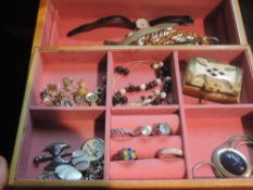A wooden jewellery box containing a selection of costume and silver jewellery including rings,