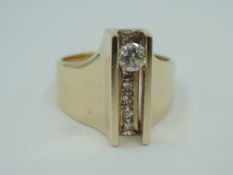 A yellow metal dress ring of stylised form stamped 14K having a row of six channel set diamonds with