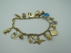 A yellow metal charm bracelet stamped 585 having 17 charms including book, playing cards, mouse,