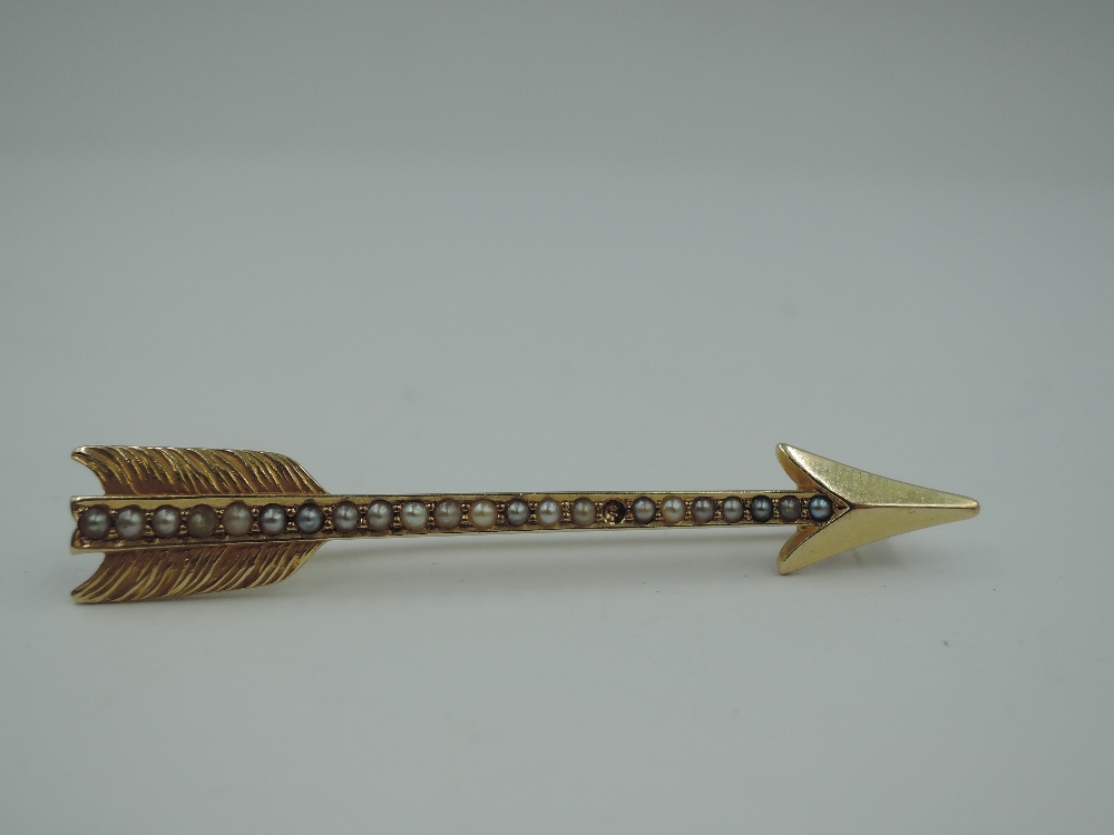 A yellow metal brooch stamped 14K in the form of an arrow having split pearl decoration, one pearl