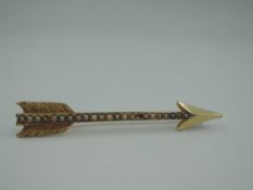 A yellow metal brooch stamped 14K in the form of an arrow having split pearl decoration, one pearl