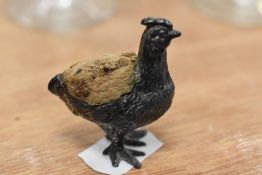 A late Victorian pin cushion of a small pewter cast hen or chicken