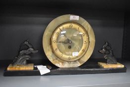 An art deco mantle clock having stone cut surround and a pair of stylised deer figures