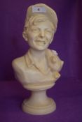 A vintage stone or mineral bust of a cheeky Butchers lad with jaunty hat and cigarette with a pig or