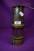 A vintage coal miners safety lamp with a brass and cast shell