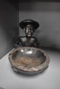 An ethnic wood carved figure of a tribal man holding a dish