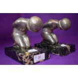 A pair of art deco book ends on marble bases of two nude kneeling ladies