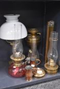 A selection of oil burners and lamps including cranberry glass well and brass Roman column style