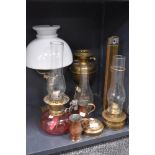 A selection of oil burners and lamps including cranberry glass well and brass Roman column style