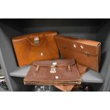 Three leather brief cases or satchels, and one similar cardboard example.