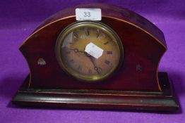 An early 20th century mantel clock having mahogany body and roman numerals to face.