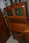 A traditional golden oak bureau bookcase in the Arts and Crafts style, having coloured and leaded
