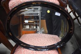 A traditional black laquer work oval wall mirror, width approx. 58cm