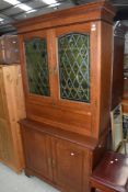 A traditional golden secretaire bureau bookcase in the Arts and Crafts style, having coloured and