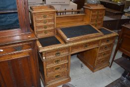 A Victorian golden oak desk having central writing slope flanked by four stationery drawers to