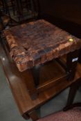 An Arts and Crafts leather strapped stool having heavy oak frame