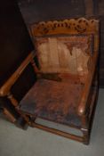 An early 20th Century golden oak monks chair of typucal form, seat and back in disrepair but frame
