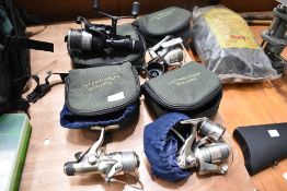 Four fishing spinning wheels in cases including Okuma Abu Garcia and Shimano
