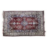 A PERSIAN SILK RUG of rectangular form with lozenge shaped centre field in claret red, enclosed by