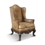 A GEORGE III STYLE WINGBACK ARMCHAIR, covered in light brown close nail leather upholstery, with