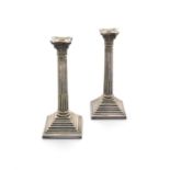 A PAIR OF SILVER PLATED TABLE CANDLESTICKS, of Corinthian column form, raised on square stepped