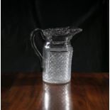 A CUT GLASS WATER JUG, 19th Century, with serrated rim over panels of flat cut flutes, above a