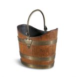 A LATE VICTORIAN BRASS BOUND GOLDEN OAK FUEL BUCKET, of oval form, with swing handle.